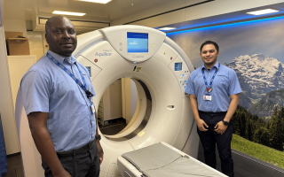 Two radiographers standing by the CT scanner